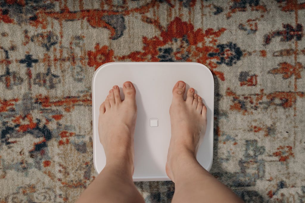 Overhead view of feet on a smart scale atop a decorative carpet, focusing on balance and health.