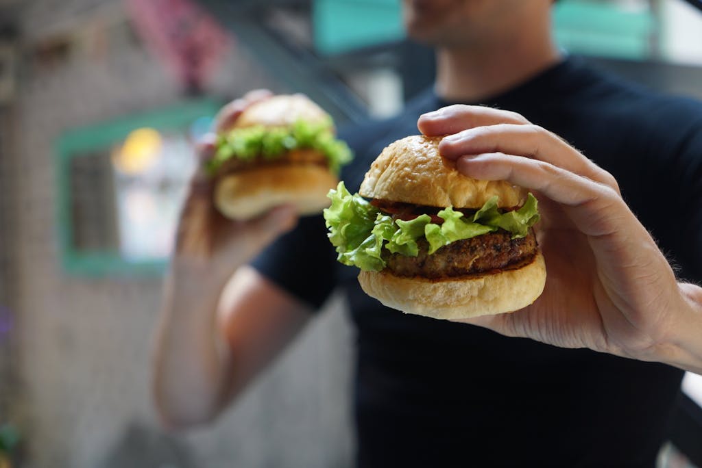 Why Tracking Your Food Might Be the Wake-Up Call You Need A close-up shot of a person holding a homemade burger with fresh lettuce, ideal for fast food themes.