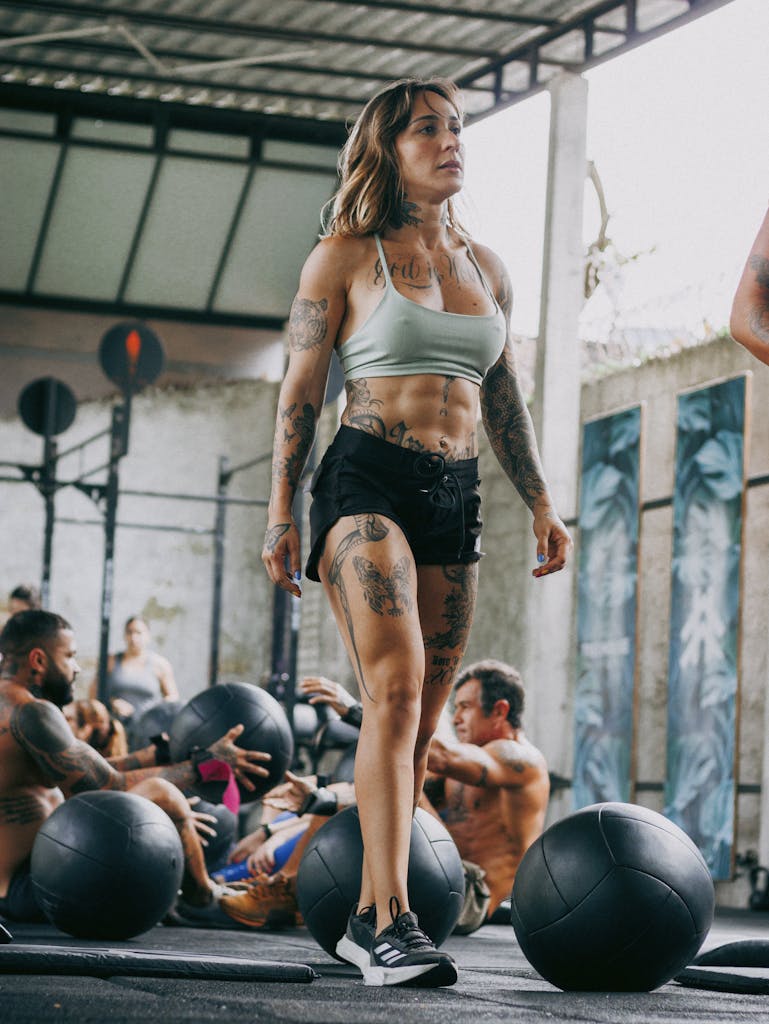 motivation fades in almost every fitness journey. Tattooed woman leading a CrossFit class outdoors, emphasizing fitness and motivation.